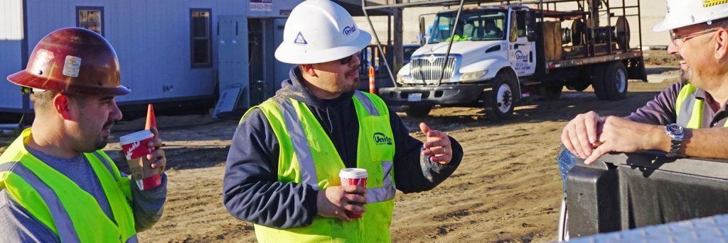 three united site services employees drinking coffee on a construction jobsite