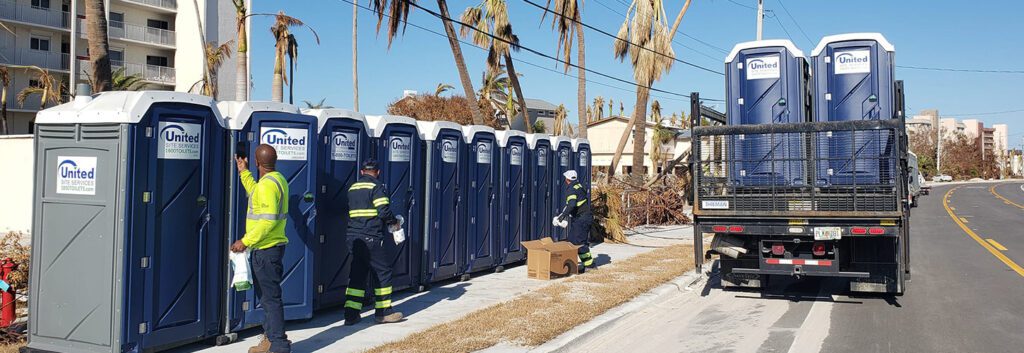 3 service techs cleaning a row of porta potties