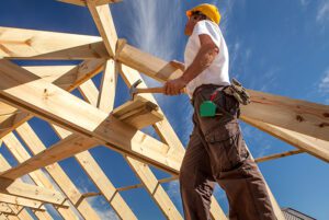 a man building a roof on a house with hammer in hand