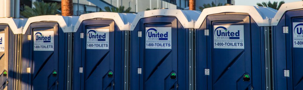 six porta potties in a row at an outdoor event