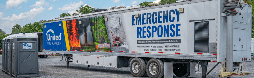 Large white trailer with "Emergency Response" written on it, and three portable restrooms standing to the left side.